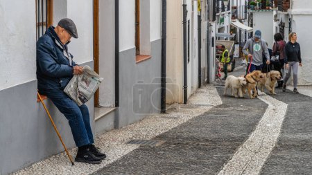 Téléchargez les photos : Grenade, Espagne, 14 février 2024. Messieurs lisant le journal dans une rue populaire du quartier de l'Albaicin à Grenade. Photo de haute qualité - en image libre de droit