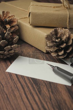Photo for Gift boxes wrapped in recycled paper and gift cards, new year gift boxes Placed on a wooden table, a copyspace and a brown Christmas gift box. - Royalty Free Image