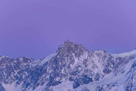 This landscape photo was taken in Europe, in France, Rhone Alpes, in Savoie, in the Alps, in winter. You can see the Aiguille du Midi in the Mont Blanc massif at nightfall, under the sun.