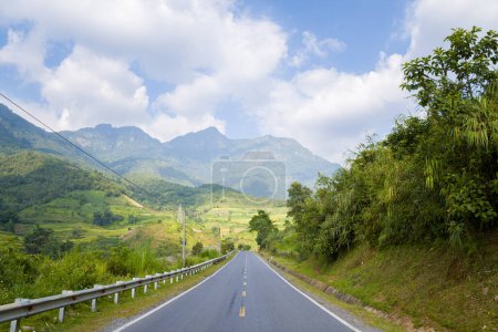 Téléchargez les photos : Cette photo de paysage a été prise, en Asie, au Vietnam, au Tonkin, entre Lai Chau et Sapa, en été. On voit une route asphaltée au milieu de la campagne et des montagnes, sous le soleil. - en image libre de droit
