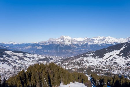 Foto de Esta foto de paisaje fue tomada en Europa, en Francia, en los Alpes del Ródano, en Saboya, en los Alpes, en invierno. Vemos la ciudad de Megeve en medio de las montañas del macizo del Mont Blanc, bajo el sol. - Imagen libre de derechos