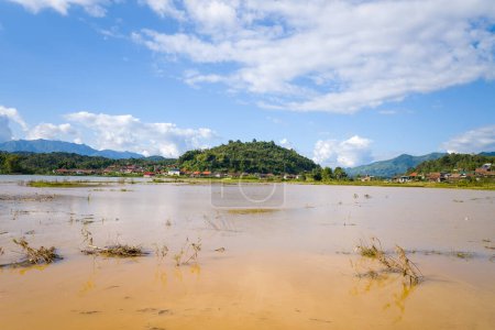 This landscape photo was taken, in Asia, in Vietnam, in Tonkin, in Dien Bien Phu, in summer. We see a lake and the flooded rice fields in the green countryside on the edge of the mountains, under the Sun.