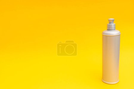 Foto de Botella de champú gris sobre fondo amarillo - Imagen libre de derechos