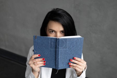 Téléchargez les photos : Une femme en chemise blanche avec une coupe de cheveux courte, un écrivain, tenant un cahier - en image libre de droit