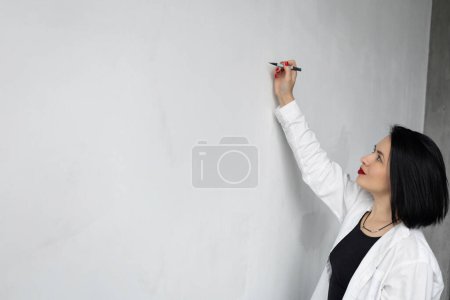 Téléchargez les photos : Femme en chemise blanche avec coupe courte, écrivain, écriture sur le mur, photo horizontale pour la publicité - en image libre de droit