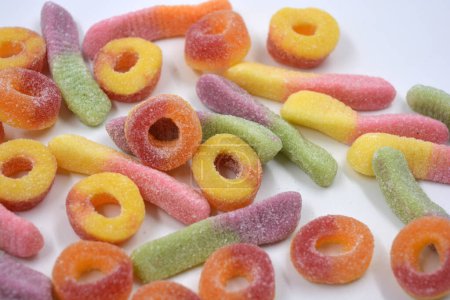 Photo for Beautiful and bright colored sweets of children's candies in the form of sweet earthworms of different colors, American donuts, lollipops arranged on a white matte background. - Royalty Free Image