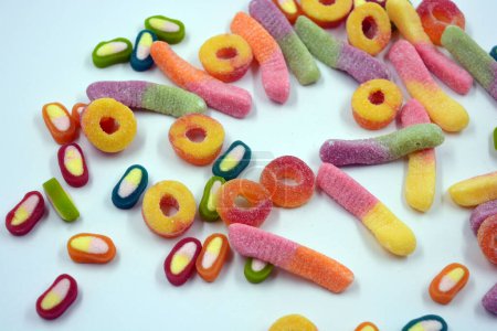 Photo for Beautiful and bright colored sweets of children's candies in the form of sweet earthworms of different colors, American donuts, lollipops arranged on a white matte background. - Royalty Free Image
