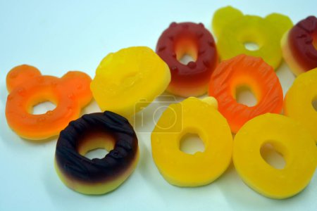 Photo for Beautiful and bright colored sweets in the form of sweet different colors American doughnuts arranged on a white matte background. - Royalty Free Image
