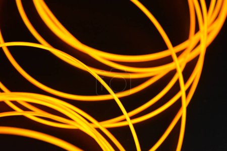 Foto de Un caos brillante de alambres finos y brillantes. Un inusual, único fondo brillante de cables delgados apilados caóticamente, naranja, amarillo, arnés brillante rojo, alambre iluminado, delgado colocado sobre un fondo delgado. - Imagen libre de derechos