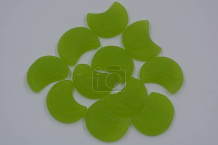 Foto de Caramelos gomosos infantiles brillantes y de alta calidad en forma de luna verde, talismanes situados sobre un fondo blanco. - Imagen libre de derechos