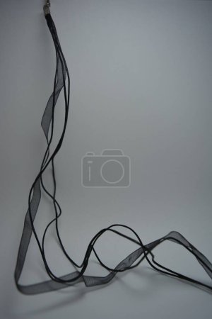 Foto de Hermosas cuerdas largas negras pequeñas, cinta negra transparente bellamente colocada sobre fondo blanco. - Imagen libre de derechos