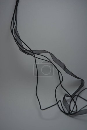 Foto de Hermosas cuerdas largas negras pequeñas, cinta negra transparente bellamente colocada sobre fondo blanco. - Imagen libre de derechos