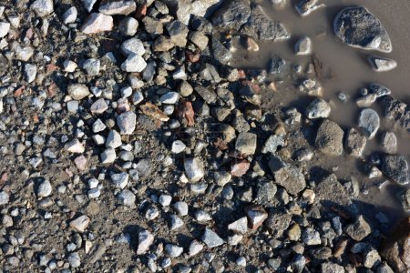 Natur, Mineralien, Granit, graue Steine und Krümel, rote kleine Ziegel, die über die sandige Oberfläche der Erde verstreut sind.
