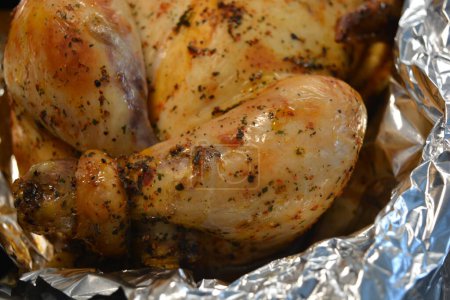 Beautiful, deliciously cooked marinated chicken in the oven. Chicken with golden, toasted skin wrapped in silver foil.