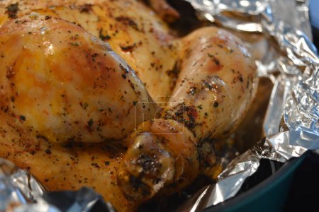 Beautiful, deliciously cooked marinated chicken in the oven. Chicken with golden, toasted skin wrapped in silver foil.