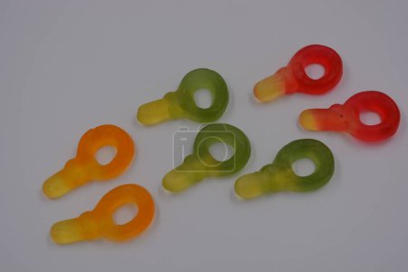 Foto de Caramelos inusuales y no estándar de color verde gelatina, amarillo, rojo, amarillo, naranja en forma de llave dispuesta sobre un fondo de plástico blanco. - Imagen libre de derechos