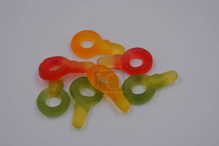 Foto de Caramelos inusuales y no estándar de color verde gelatina, amarillo, rojo, amarillo, naranja en forma de llave dispuesta sobre un fondo de plástico blanco. - Imagen libre de derechos