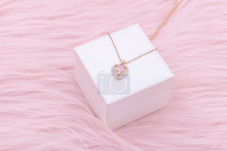 Photo for Necklace jewelry, Close up of a heart shape gemstone with a gold chain necklace on pink background. An elegant necklace for valentine's day. - Royalty Free Image