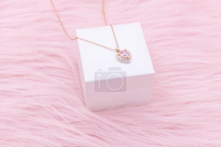 Necklace jewelry, Close up of a heart shape gemstone with a gold chain necklace on pink background. An elegant necklace for valentine's day.
