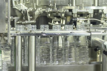 Foto de Las botellas de agua potable vacías en la cinta transportadora para el proceso de llenado. La alta tecnología del proceso de llenado de agua potable. - Imagen libre de derechos
