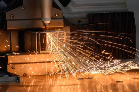 Nahaufnahme Szene der Faser-Laser-Schneidemaschine schneiden die quadratische Form Edelstahlrohr mit funkelndem Licht. Der hochtechnologische Prozess der Blechherstellung mittels Laserschneidmaschine. 