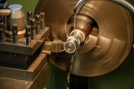 The lathe machine finish cut the metal shaft parts with liquid coolant method. The metalworking process by turning machine.