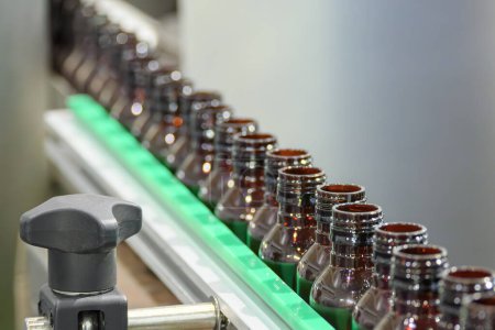 Foto de Las botellas de droga vacías en la cinta transportadora para el proceso de llenado. La alta tecnología del proceso de llenado de agua potable. - Imagen libre de derechos