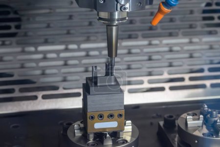La fraiseuse CNC coupe les pièces d'électrode en graphite. Le processus de fabrication de moules et de matrices par centre d'usinage CNC.