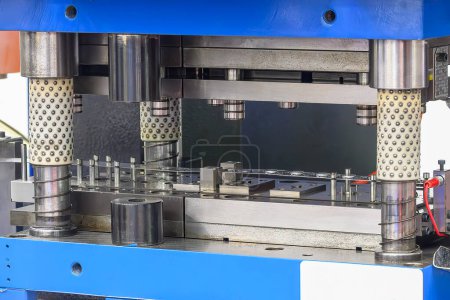El proceso de mecanizado por matriz progresiva en la escena azul claro. El equipo metalúrgico para el proceso de fabricación.