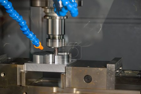 Die CNC-Fräsmaschine schneidet Werkzeugteile mit flachem Schaftfräswerkzeug in der hellblauen Szene. Schneiden von Formteilen durch Bearbeitungszentrum mit solidem Schaftfräser.