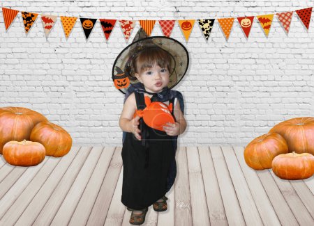 Foto de Niña, bebé en traje de bruja con caldero mágico y calabaza de Halloween - Imagen libre de derechos