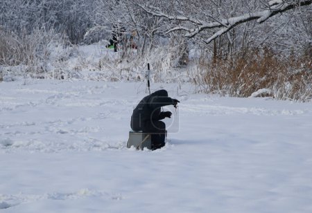 Foto de Solitario hombre hielo pesca en congelado lago - Imagen libre de derechos