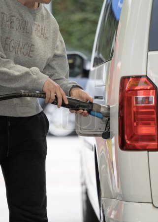 Foto de Mujer mete gas natural en su coche en una gasolinera. - Imagen libre de derechos