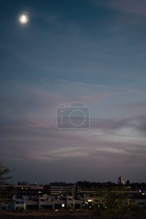 Photo for Skyline of Alcobendas with Madrid city center in the background at night. Sunset sky clouds and moon with copy space. - Royalty Free Image