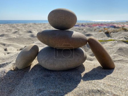 Téléchargez les photos : Gros plan de Petit monticule de pierre Apacheta avec forme humaine sur la plage de sable fin ensoleillée. Équilibre de vie, harmonie et concept de paix. - en image libre de droit