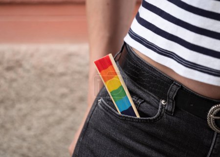 Nahaufnahme einer schwulen Person mit einem regenbogenfarbenen spanischen Fächer in der Tasche als Zeichen zur Unterstützung der LGBTQ-Community.