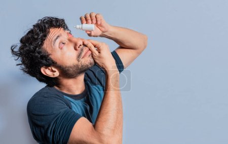 Photo for Person applying dropper to irritated eye. People applying refreshing drops to irritated eye. Man putting a dropper in his eye isolated. Man with irritated eye applying drops with a dropper - Royalty Free Image