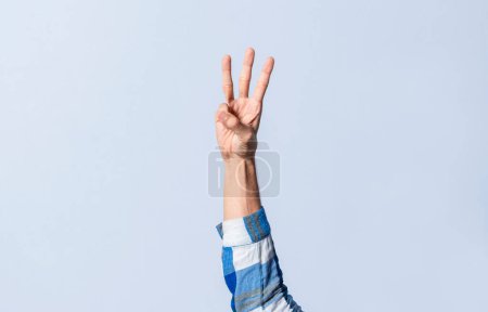 Photo for Hand gesturing the letter W in sign language on an isolated background. Man's hand gesturing the letter W of the alphabet isolated. Letter W of the alphabet in sign language - Royalty Free Image