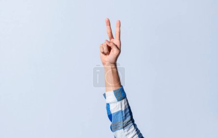 Photo for Hand gesturing the letter V in sign language on an isolated background. Man's hand gesturing the letter V of the alphabet isolated. Letter V of the alphabet in sign language - Royalty Free Image