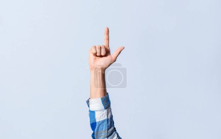 Photo for Hand gesturing the letter L in sign language on an isolated background. Man's hand gesturing the letter L of the alphabet isolated. Letters of the alphabet in sign language - Royalty Free Image