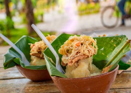 Die kräftige typische Küche von Granada, Nicaragua. Traditioneller Vigoron in Bananenblättern, serviert auf einem Holztisch. Nicaragua Food-Konzept, Close-up von zwei vigorones serviert auf einem Holztisch