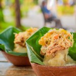 Close-up of two vigorones served on a wooden table. The vigoron typical food of Granada, Nicaragua. Traditional Vigoron in banana leaves served on a wooden table. Nicaragua food concept