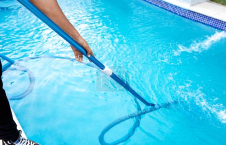 Photo for Pool maintenance and cleaning with vacuum hose. People cleaning swimming pool with suction hose. Close-up of man cleaning a swimming pool with a vacuum hose - Royalty Free Image