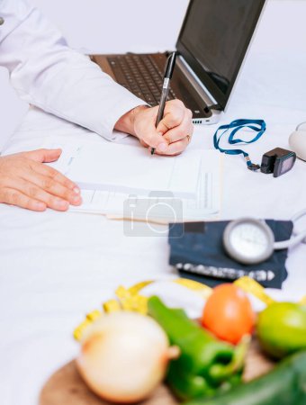 Téléchargez les photos : Hands of male nutritionist taking notes at his desk, Nutritionist hands taking medical records in the office. Close-up of nutritionist writing on notepad - en image libre de droit