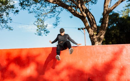 Photo for Young man doing jumping parkour at sunset. Guy doing wall jump parkour, Artistic image of man doing parkour - Royalty Free Image