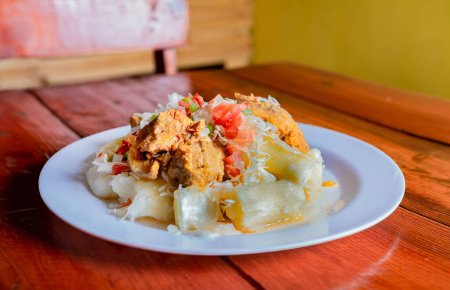 Photo for Traditional Chancho dish with Yuca. Nicaraguan pork with yucca served on wooden table - Royalty Free Image