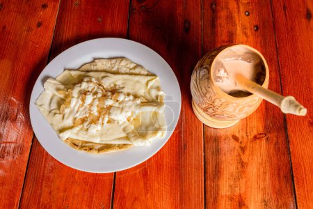 Photo for Delicious traditional Quesillo with cocoa drink. Quesillo plate with cocoa drink served on wooden table. Typical Nicaraguan food and drinks. - Royalty Free Image