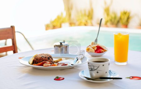 Nahaufnahme eines traditionellen Frühstücks auf einem Tisch mit einem Pool im Hintergrund. Morgens Frühstück auf dem Tisch neben einem Schwimmbad