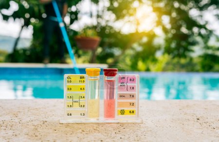 Foto de Kit de probador para medir cloro y ph en piscinas. Kit de probador de agua de la piscina PH en el borde de la piscina - Imagen libre de derechos