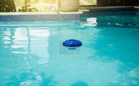 Foto de Un cloro flota en una piscina. Flotador dosificador para la cloración de la piscina, dispensador de cloro en una hermosa piscina - Imagen libre de derechos